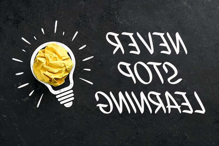 Image shows a chalkboard with the words "Never Stop Learning" and a drawn on lightbulb with crumpled yellow paper in the bulb portion.